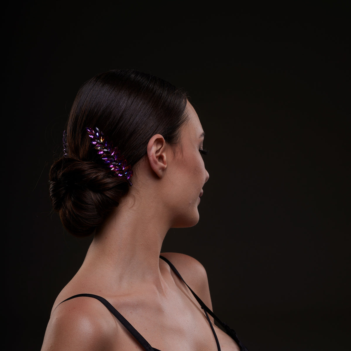 Woman with a decorative hair clip in her hair against a dark background